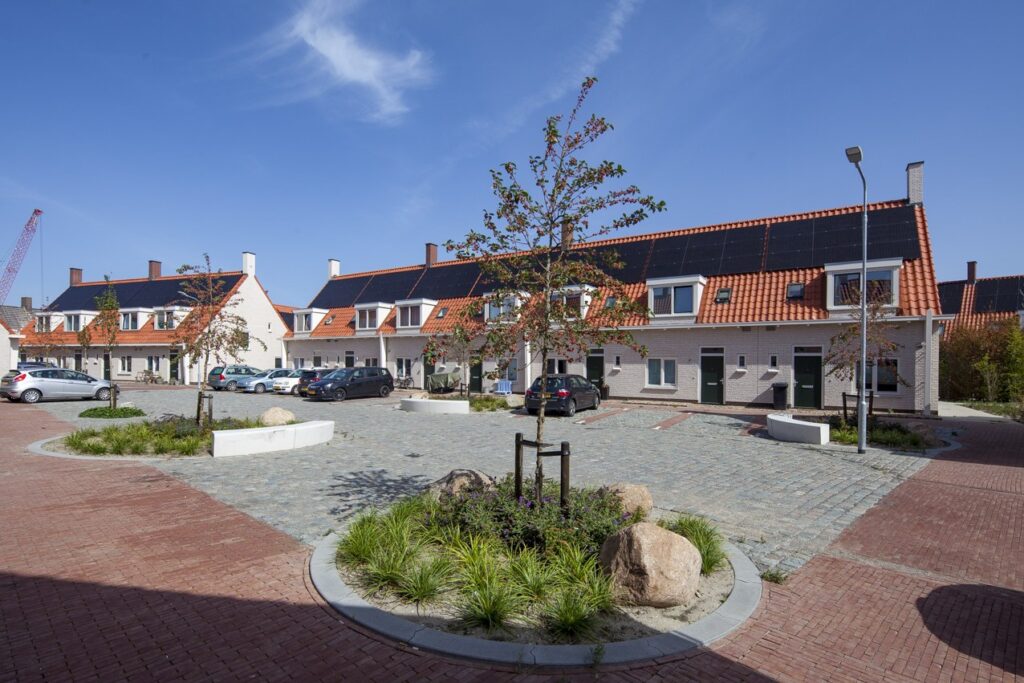 Overzicht van de vernieuwde sociale huurwoningen rond een groen hof in 't Zand